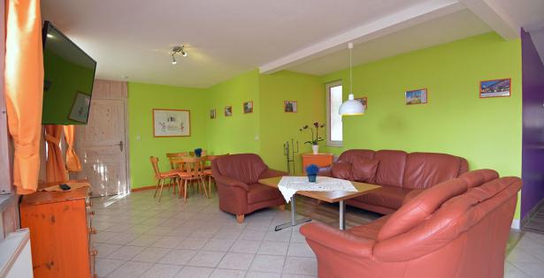 Wohnzimmer mit Couch, Sesseln und TV