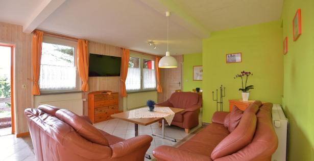 Wohnzimmer mit Couch, Sesseln und TV